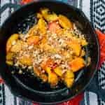 Peach crisp in a cast iron skillet on a table