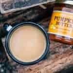 A mug and a jar of pumpkin butter on a log