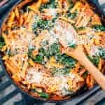 Pasta topped with cheese in a cast iron skillet over a campfire