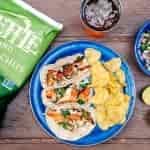 Three campfire grilled fish tacos on a blue camping plate.