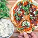 Michael picking up a slice of pizza off of a cutting board