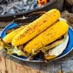 Grilled corn on the cob stacked on a blue plate.