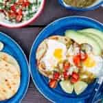 Eggs, salsa, and avocado on top of tortillas on blue camping plates.